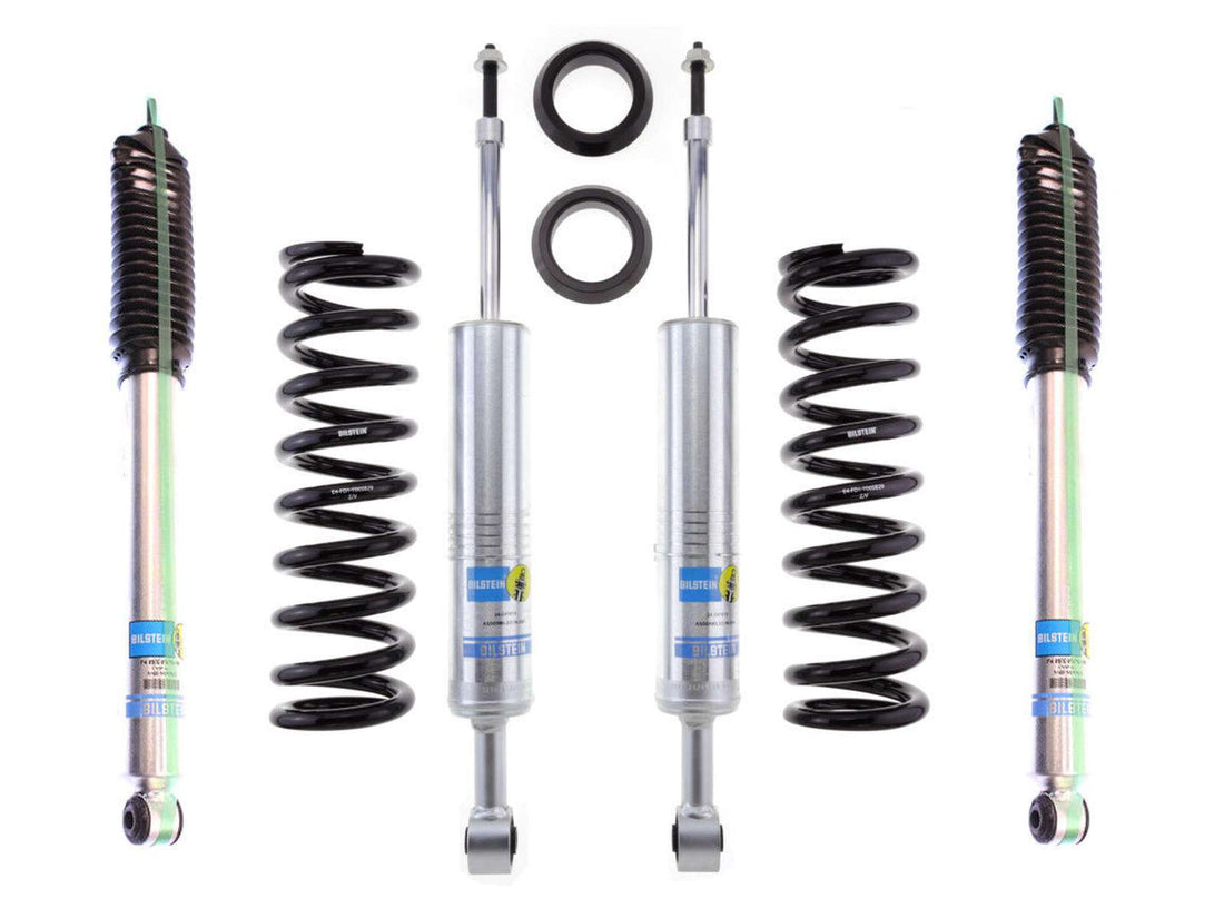 A set of vehicle suspension components, including LTW Motorsports' 96-04 Toyota Tacoma 6 Lug Leveling Kit with Bilstein 6112 Struts and Rear 5100 Shocks, accompanied by two coil springs and additional mounting hardware, all arranged symmetrically against a white background.