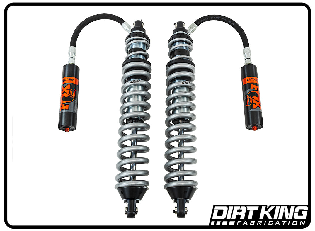 The image showcases a pair of Dirt King 07-18 GM 1500 Long Travel Spec Fox Coilovers from DIRT KING SHOCKS, perfect for off-road performance. Each coilover features a silver coil spring around a blue piston with black and orange reservoir tanks attached by hoses. The DIRT KING SHOCKS logo is at the bottom right.